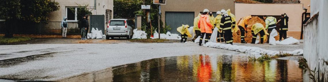 Emergency responders in reflective gear addressing floodwaters on a residential street.